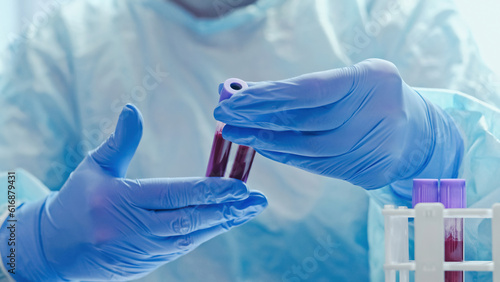 Blood diagnostics. Laboratory analysis. Microbiology test. Medical worker with hands in protective rubber gloves studying examining samples tubes. photo