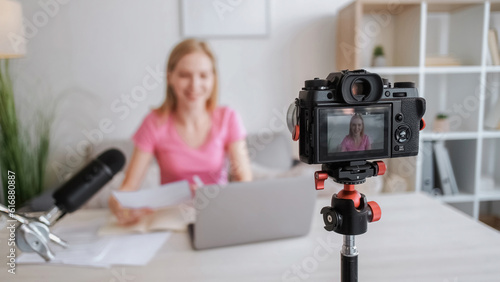 Camera recording. Digital media. Online business. Filming equipment. Smiling female blogger woman on video shooting device screen on tripod creating content.