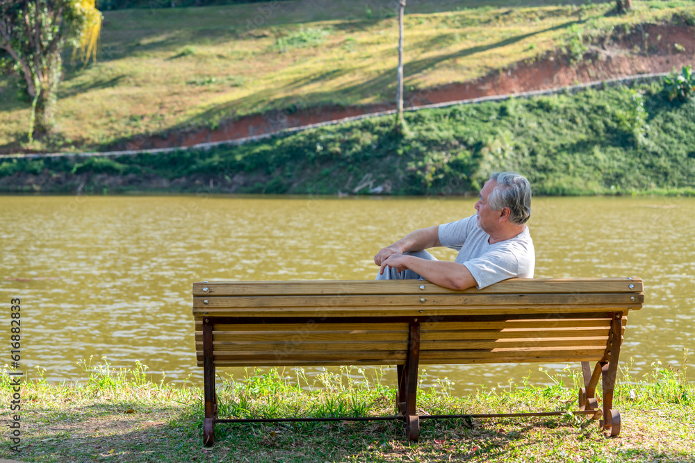 Loneliness Asian senior man sitting alone on outdoor bench in public park. Depressed elderly retirement male feeling lonely, sad and boredom. Old people mental health, illness recovery concept Loneliness Asian senior man sitting alone on outdoor bench in public park. Depressed elderly retirement male feeling lonely, sad and boredom. Old people mental health, illness recovery concept