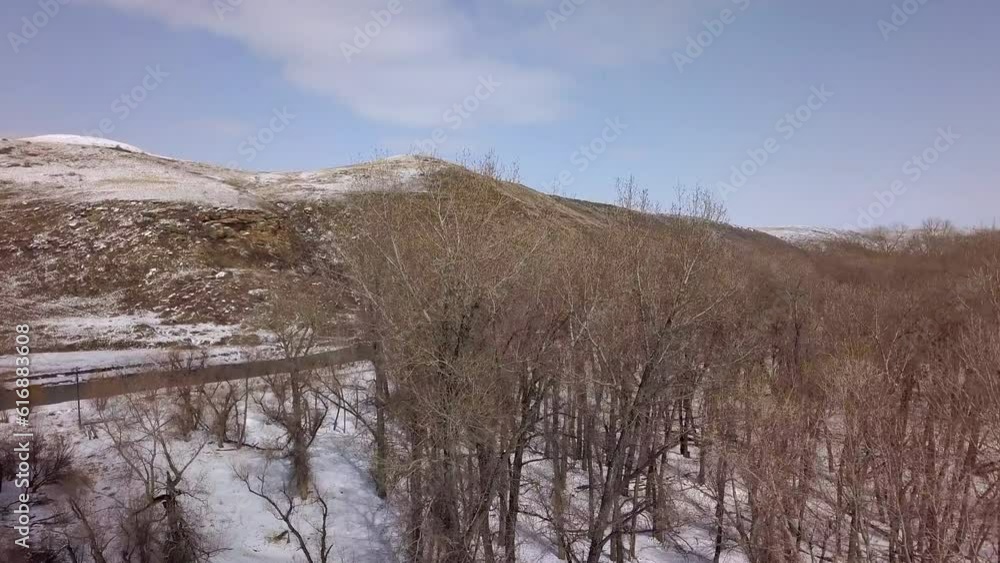 Aerial: Drone Flying Forward Over Bare Trees On Snow Near River And Mountain Range Against Sky - Billings, Montana Aerial: Drone Flying Forward Over Bare Trees On Snow Near River And Mountain Range Against Sky - Billings, Montana