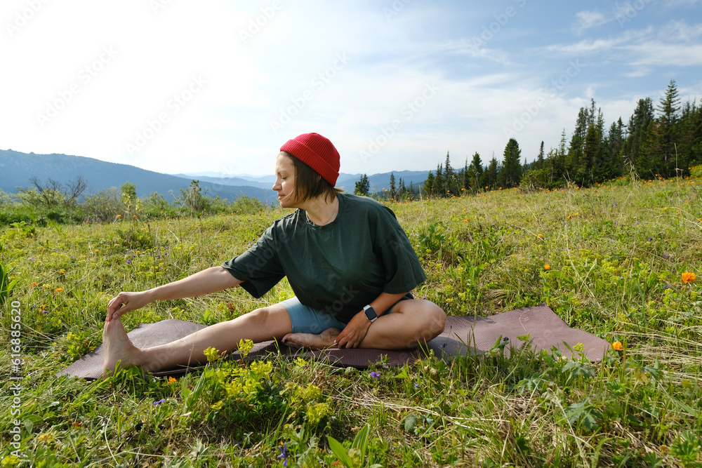 Wman doing yoga on blossom meadow and mountains background. Morning healthy activity. Wman doing yoga on blossom meadow and mountains background. Morning healthy activity.