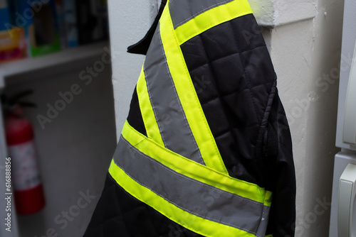 A view of a hi-vis utility jacket hanging on a wall hook. photo