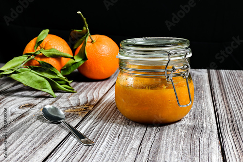 Delicious homemade orange jam in a glass jar. Homemade dessert. Horizontal photo with black background.