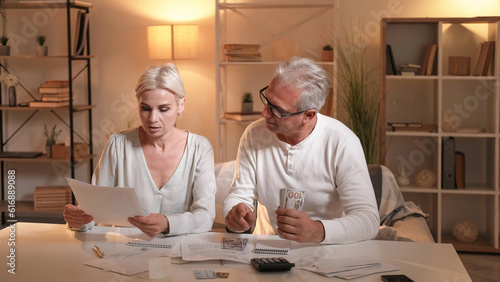 Bills payments. Family money. Couple budget. Husband wife arranging currency sitting table in light shadow room interior.