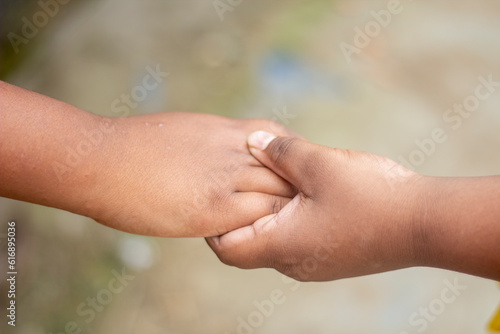 A boy holds the fingers of another boy with his hands and the background is blurred behind them © Rokonuzzamnan