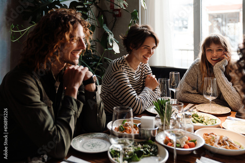 Photography Group of cheerful friends talking while dining in restaurant