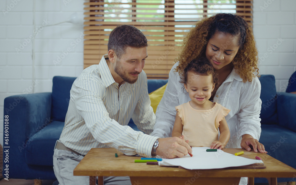 Dad, Mom and little daughter drawing with colorful pencils on paper happy smiling.Young family spend free time together in living room at home. Dad, Mom and little daughter drawing with colorful pencils on paper happy smiling.Young family spend free time together in living room at home.