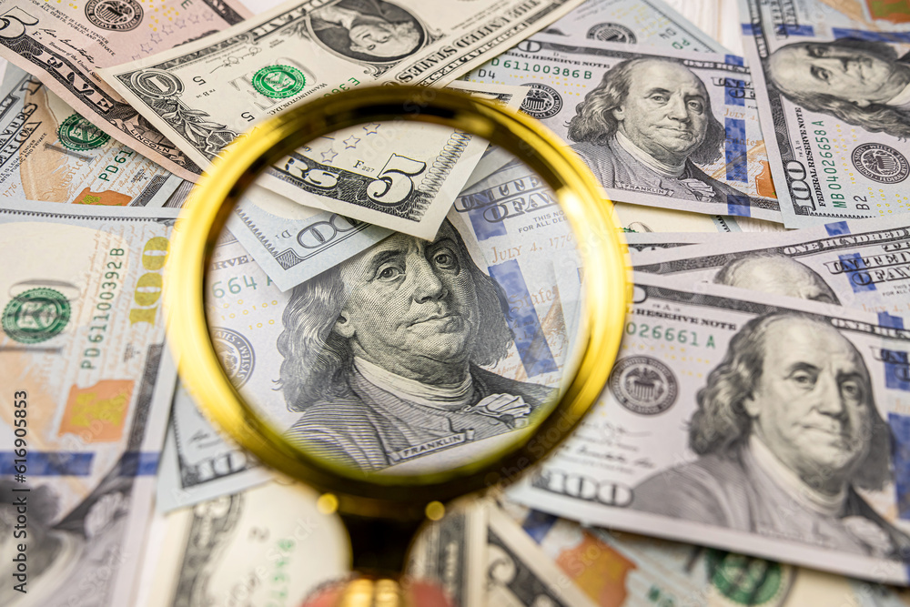 magnifying glass over different United States dollar bills magnifying glass over different United States dollar bills