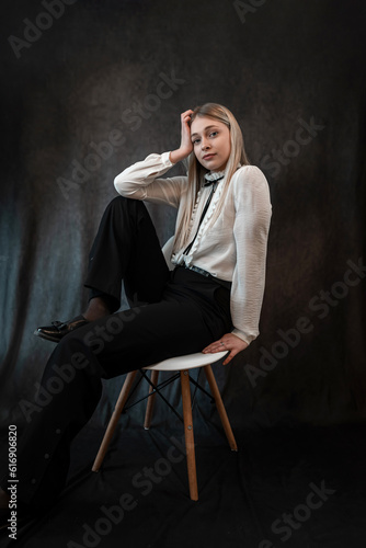 Portrait of caucasian woman wearing white blouse sitting at chair isolated dark background