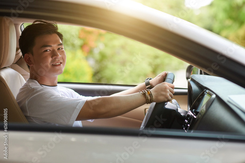 Fotografie Happy young Asian man driving car on sunny day