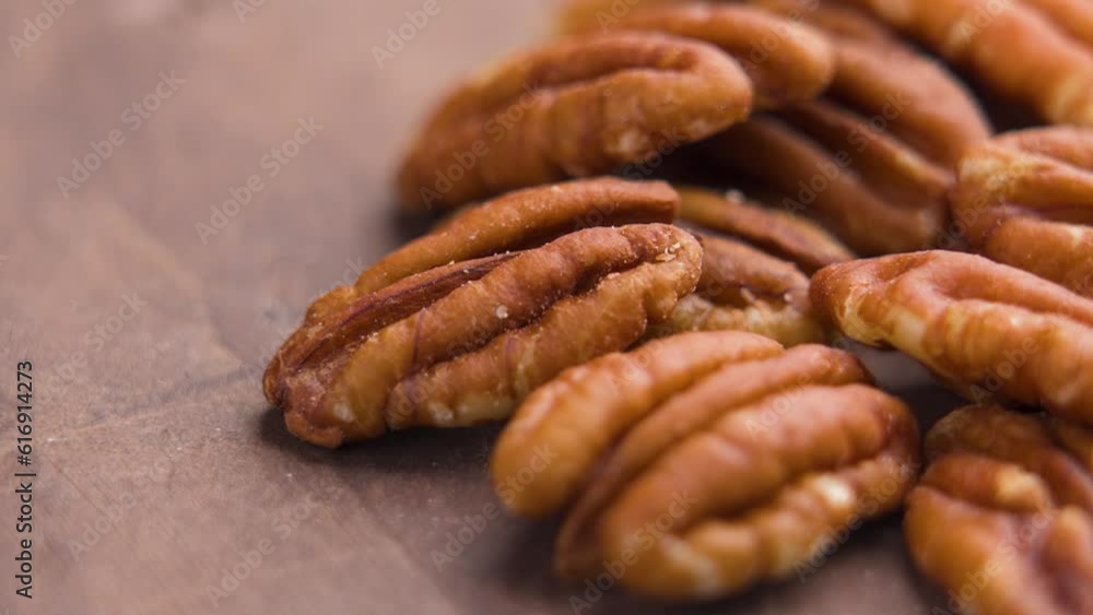 Tasty peeled pecan nuts on brown wooden surface. Rotation Tasty peeled pecan nuts on brown wooden surface. Rotation
