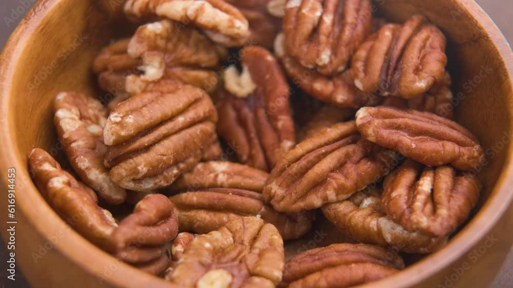 Cook hand takes raw organic pecan nut from rustic wooden bowl. Close up Cook hand takes raw organic pecan nut from rustic wooden bowl. Close up