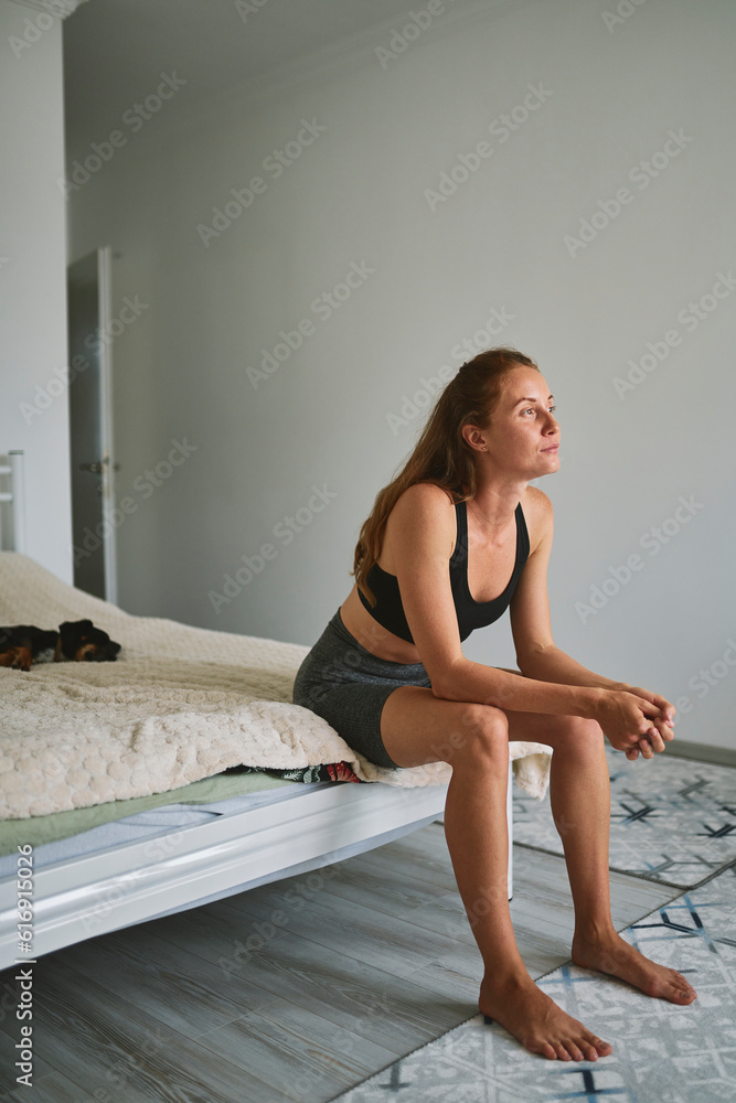 Thoughtful young woman sitting on bed at home Thoughtful young woman sitting on bed at home