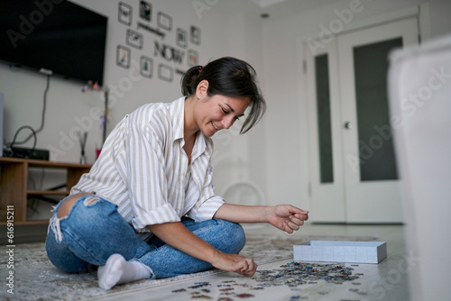 Happy woman playing puzzle at home photo