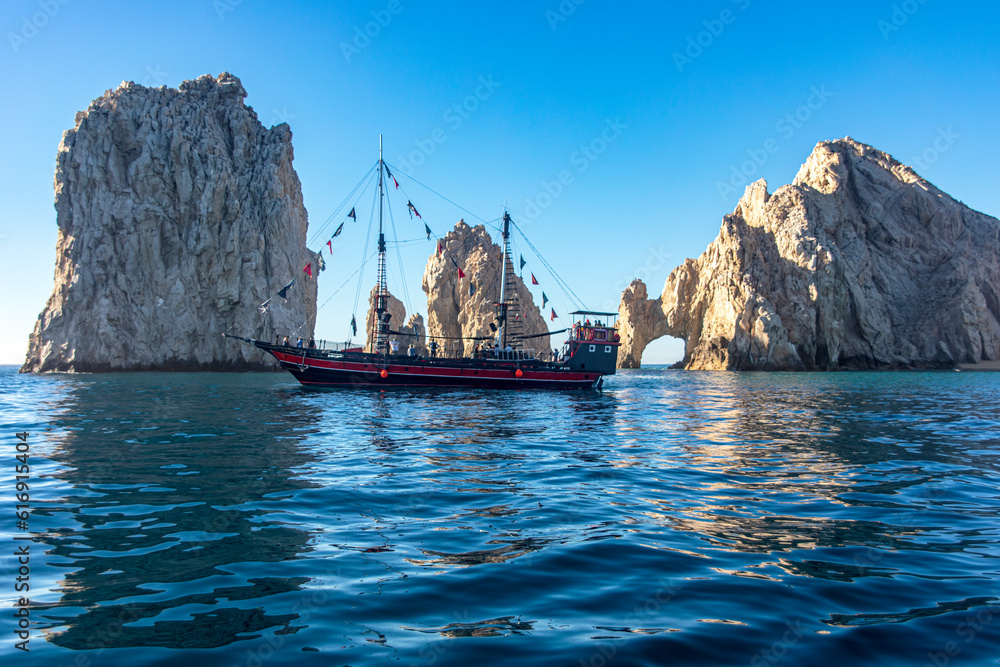 Sailboat in the arch of Cape Saint Luke, a famous rock formation known for being where the Cortez Sea meets the Pacific Ocean, in the state of Baja California Sur, Mexico. Arch concept.