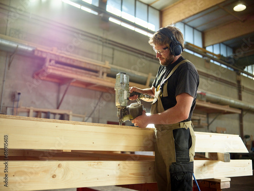 Carpenter using nail tool on timber in workshop photo