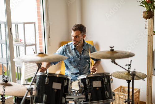Smiling young drummer playing drum at home photo