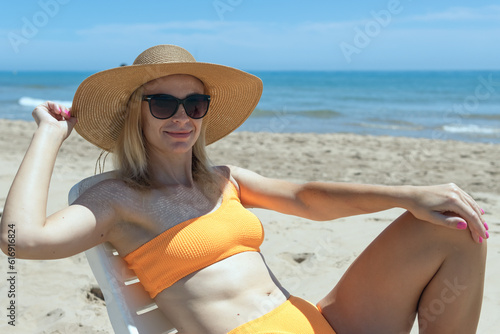 Portrait of a happy european woman in an orange swimsuit sunbathing on a plastic sun lounger