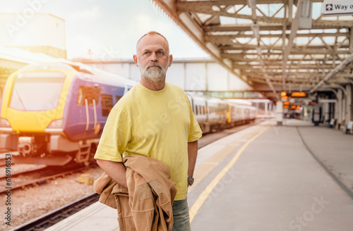 Traveler with a suitcase and suit waiting for a train at the train station. Travel concept.