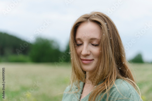 Smiling young woman with eyes closed on field photo