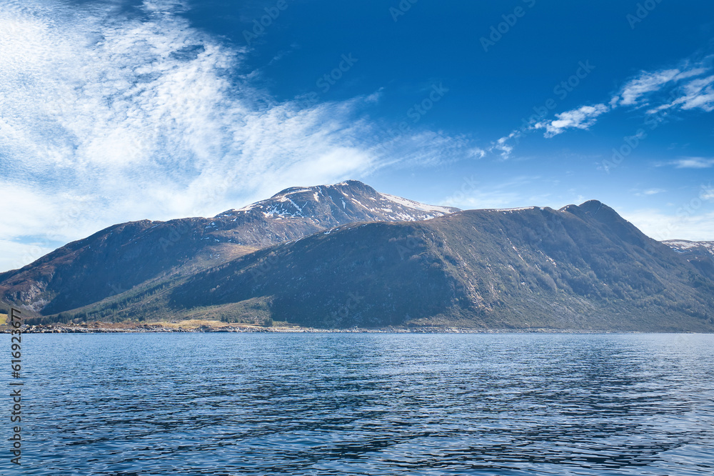 Fjord with mountains on horizon. Water glistens in the sun in Norway. Landscape