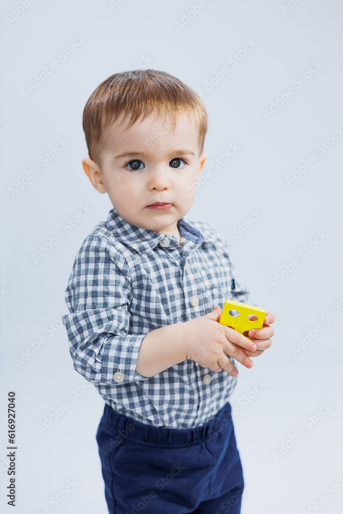 A little boy one year old on a white background with a developing wooden toy. Ecological wooden toys for small children. Child development A little boy one year old on a white background with a developing wooden toy. Ecological wooden toys for small children. Child development