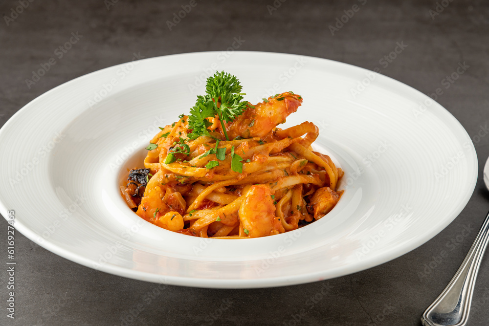 Shrimp spaghetti on white porcelain plate on black stone table