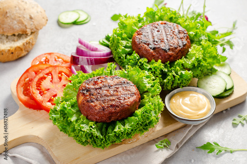 Freshly Grilled Burger Patties,Plant Based Meatless Burgers with Fresh Vegetables on a Wooden Board on Bright Background