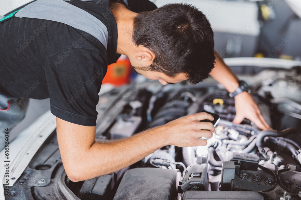 Car mechanic working in workshop checking engine Car mechanic working in workshop checking engine