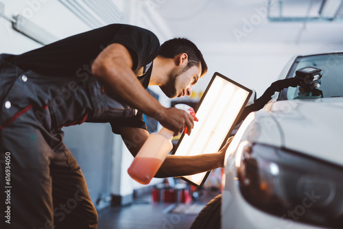 Photography Car mechanic working to remove dent in workshop.