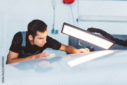 Car mechanic working to remove dent in workshop. photo