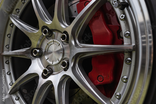 Close up of a polished alloy wheel of a sports car with red brake calipers