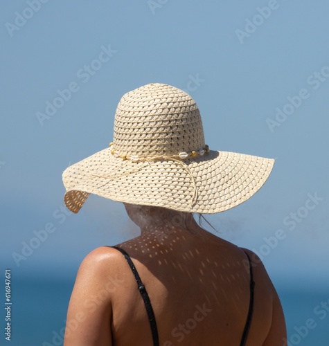 female silhouette in a hat on the background of the sky and the sea.