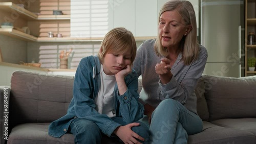Worried strict mature caucasian woman grandmother scolding lazy child grandson demand discipline angry senior female grandma punishing disobedient grandchild boy scold kid bad behavior couch at home photo