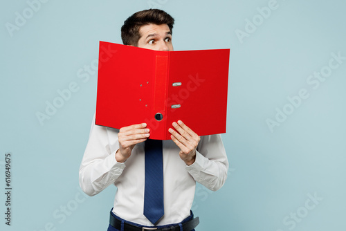 Young employee IT business man corporate lawyer wear classic formal shirt tie work in office cover mouth with red folder for papers document bookkeeping look aside isolated on plain blue background. photo