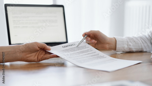 Businesswoman lawyer pointing into contract special points admitting something for colleague or client at the wooden desk in office. Business people teamwork and partnership, meeting concept