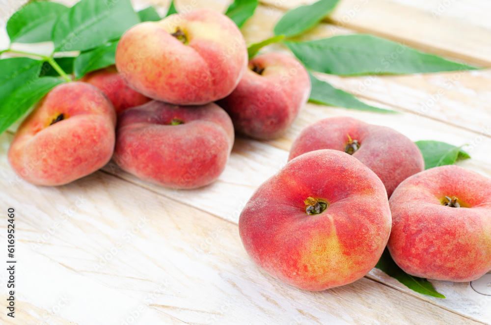Fresh Flat Peaches, Chinese Saturn Donut Peaches with Leaves on Wooden Bright Background Fresh Flat Peaches, Chinese Saturn Donut Peaches with Leaves on Wooden Bright Background