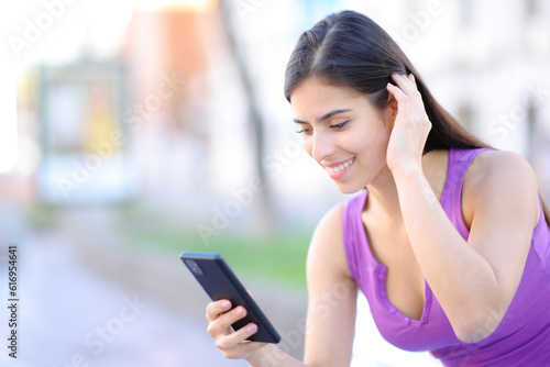 Happy woman using phone touching hair