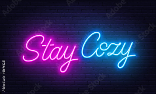 Stay Cozy neon lettering on brick wall background.