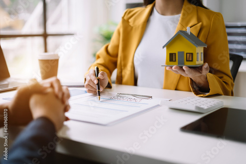 Real estate broker agent presenting and consult to customer to decision making sign insurance form agreement, home model, concerning mortgage loan offer in office