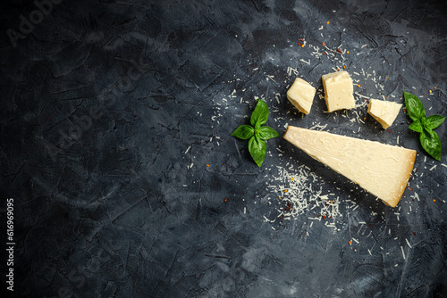 Hard cheese on black background. Parmesan. Top view. Free space for your text.