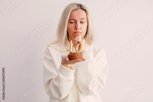 Adult unhappy beautiful woman forty years with festive cupcake with candle photo