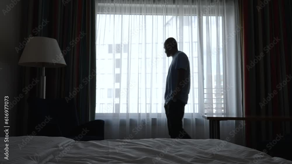 Medium shot of anxious middle-aged man pacing across dim hotel room Medium shot of anxious middle-aged man pacing across dim hotel room