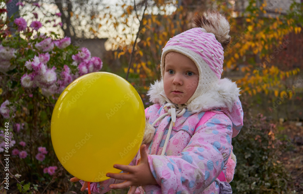 little girl in autumn with a balloon,the child holds a yellow balloon in his hands little girl in autumn with a balloon,the child holds a yellow balloon in his hands
