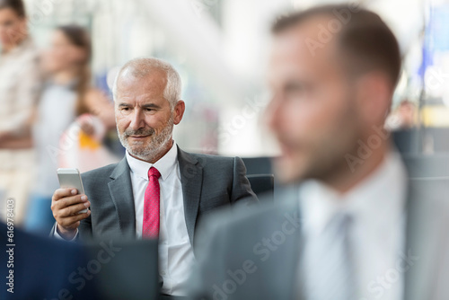 Businessman texting with cell phone in airport departure area