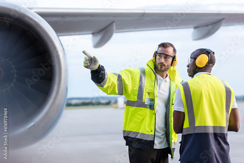 Obraz na płótnie Air traffic control ground crew workers talking near airplane on airport tarmac