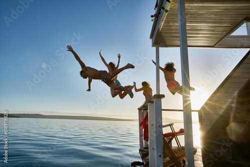 Photos Young adult friends jumping from summer houseboat into sunny ocean