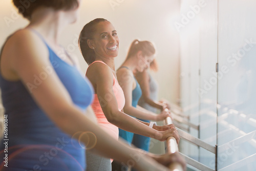 Smiling women at barre in exercise class gym studio photo