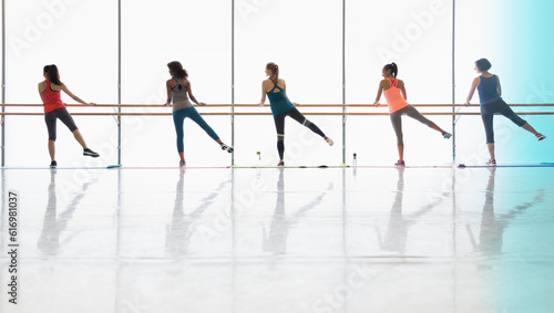 Women exercising at barre in exercise class gym studio photo