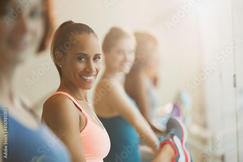 Portrait smiling women stretching legs at barre in exercise class gym studio
